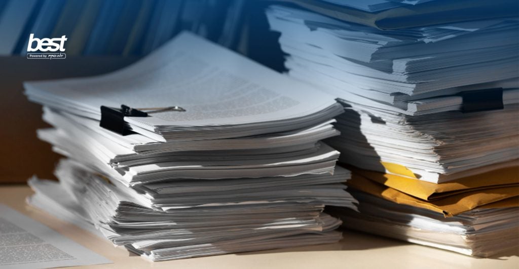 Stacks of paperwork and documents on a desk representing administrative and HR management processes